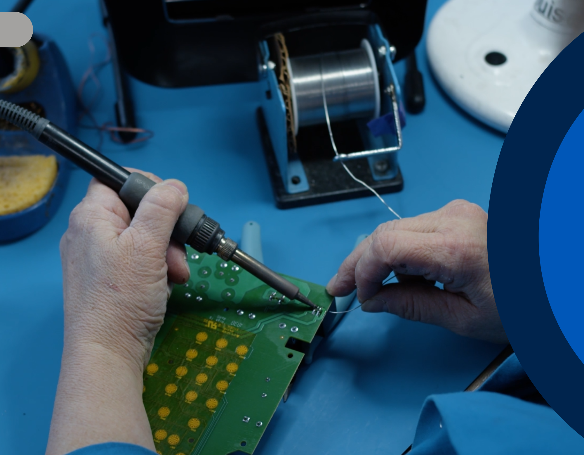 Person soldering a green circuit board to manufacture GESTAL