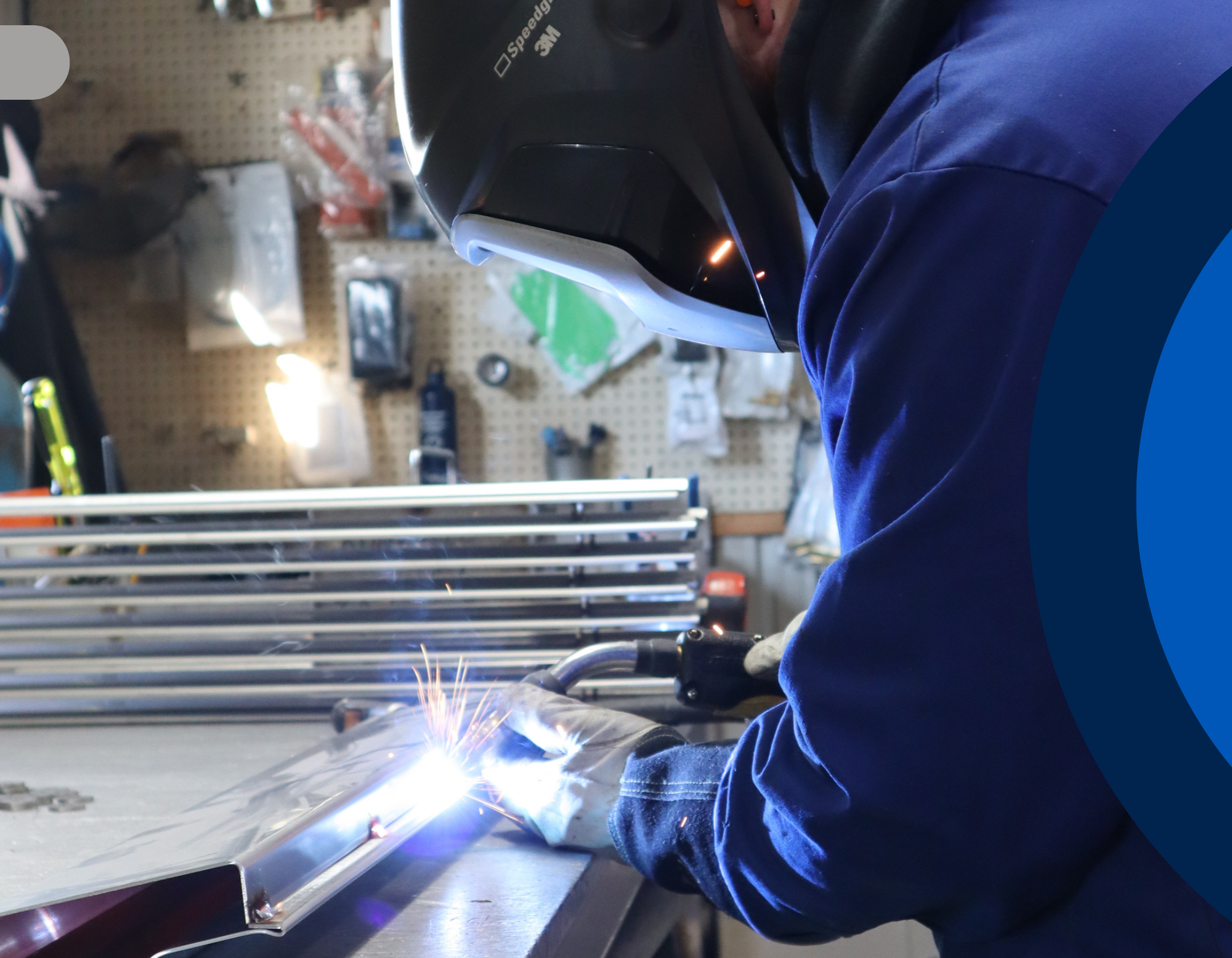 Person welding metal in a workshop with protective gear on